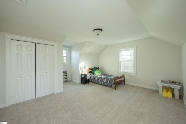 carpeted bedroom with multiple windows, vaulted ceiling, and a closet