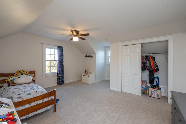 bedroom with vaulted ceiling, light colored carpet, a closet, and ceiling fan