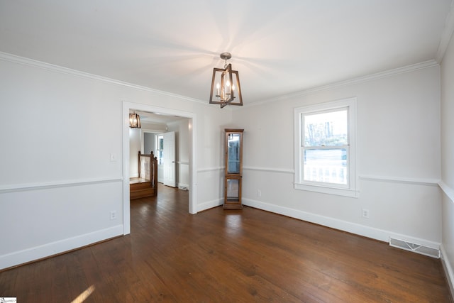 empty room featuring dark hardwood / wood-style flooring, a notable chandelier, and crown molding