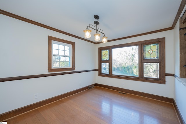 unfurnished room featuring crown molding, light wood-type flooring, and a wealth of natural light