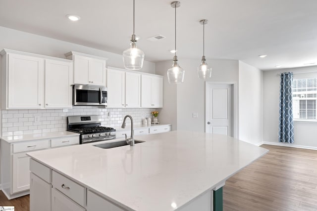 kitchen with sink, an island with sink, white cabinetry, and appliances with stainless steel finishes