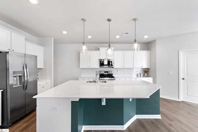 kitchen with stainless steel appliances, white cabinetry, and pendant lighting