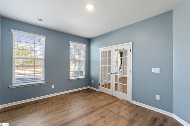 spare room featuring hardwood / wood-style flooring and french doors