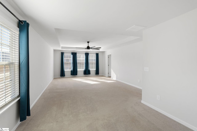 carpeted spare room with ceiling fan, a raised ceiling, and plenty of natural light