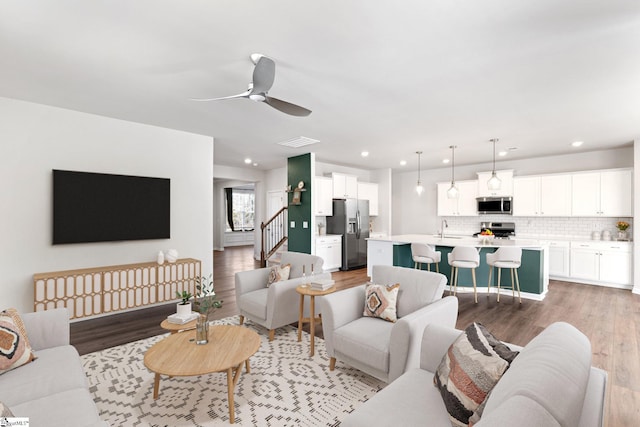 living room with sink, light hardwood / wood-style flooring, and ceiling fan