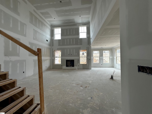 unfurnished living room featuring a towering ceiling, a fireplace, and stairs