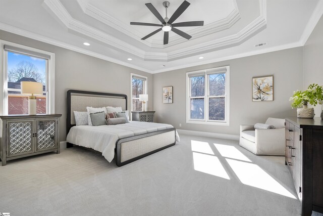 bedroom featuring light carpet, a tray ceiling, ceiling fan, and ornamental molding