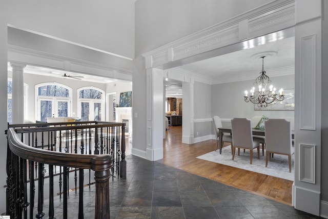 interior space featuring ceiling fan with notable chandelier, dark wood-type flooring, ornamental molding, and ornate columns