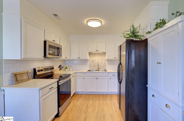 kitchen featuring light hardwood / wood-style floors, white cabinetry, sink, backsplash, and stainless steel appliances