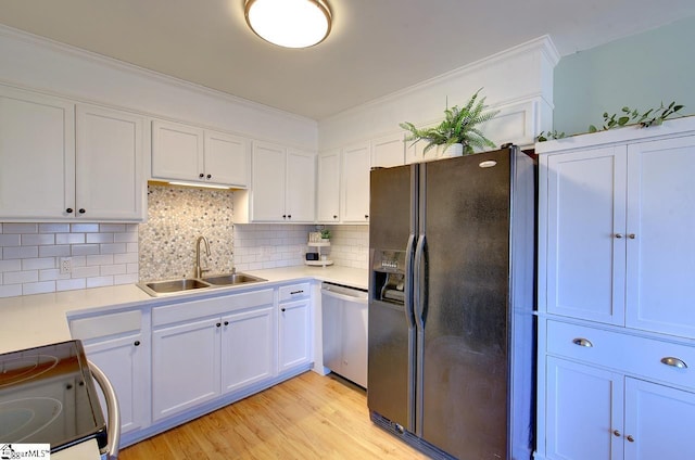 kitchen featuring appliances with stainless steel finishes, white cabinetry, tasteful backsplash, light hardwood / wood-style floors, and sink