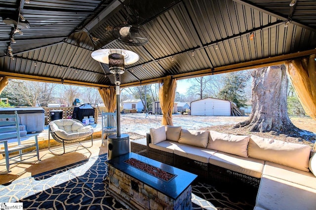 view of patio with a storage unit, ceiling fan, a gazebo, and an outdoor living space with a fire pit