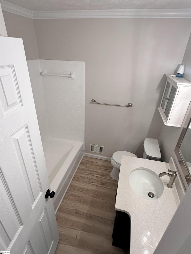 bathroom featuring wood-type flooring, a tub to relax in, vanity, toilet, and crown molding