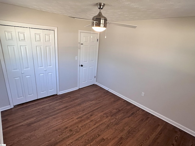 unfurnished bedroom featuring dark hardwood / wood-style flooring, a textured ceiling, a closet, and ceiling fan