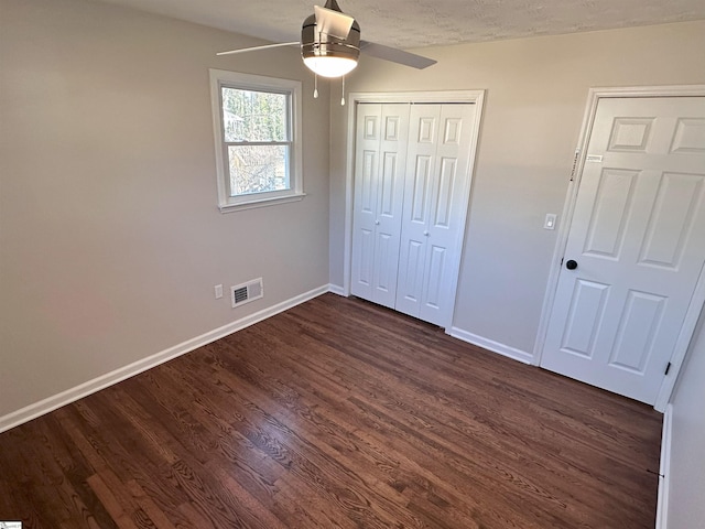 unfurnished bedroom featuring dark wood-type flooring, ceiling fan, a closet, and a textured ceiling