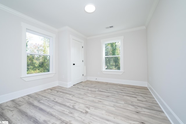 empty room featuring light wood-type flooring, a wealth of natural light, and ornamental molding