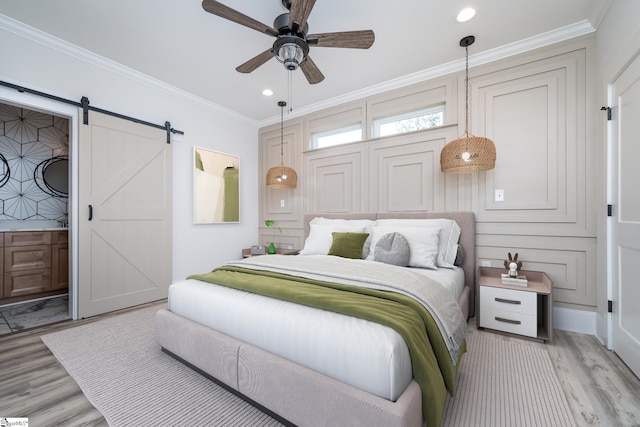 bedroom featuring light wood-style floors, a barn door, ornamental molding, and recessed lighting