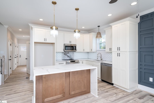 kitchen with pendant lighting, white cabinets, a kitchen island, stainless steel appliances, and light stone counters