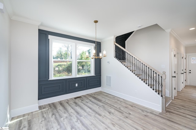 foyer entrance with crown molding, an inviting chandelier, and light wood-type flooring