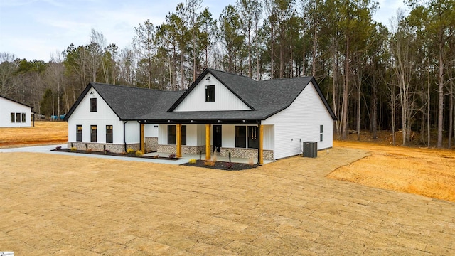 view of front of house with a front lawn, a porch, and central AC