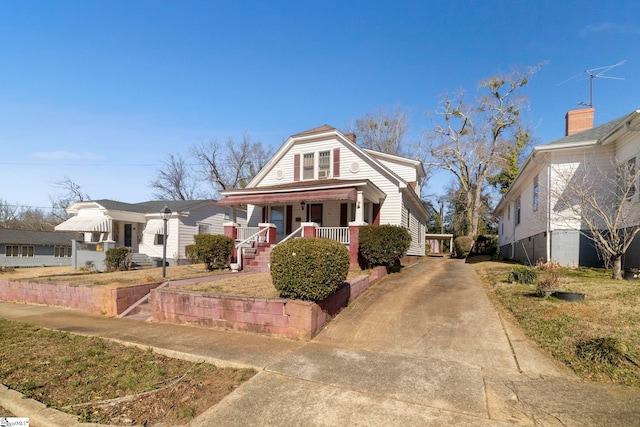 bungalow featuring covered porch and a front lawn