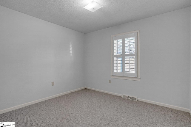 carpeted empty room featuring a textured ceiling