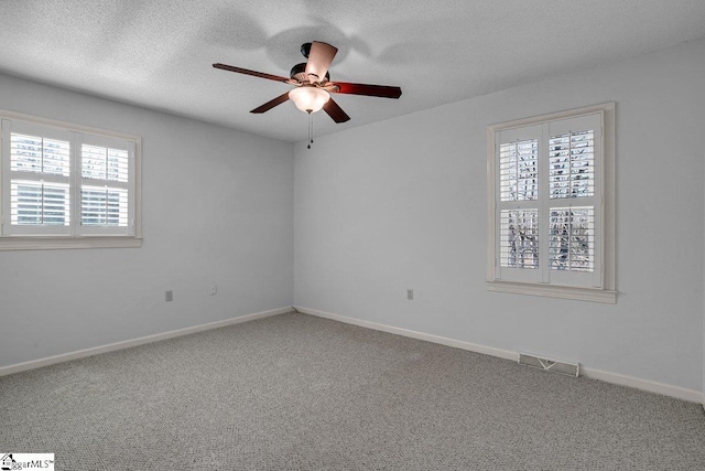 empty room featuring carpet floors, a textured ceiling, ceiling fan, and a healthy amount of sunlight