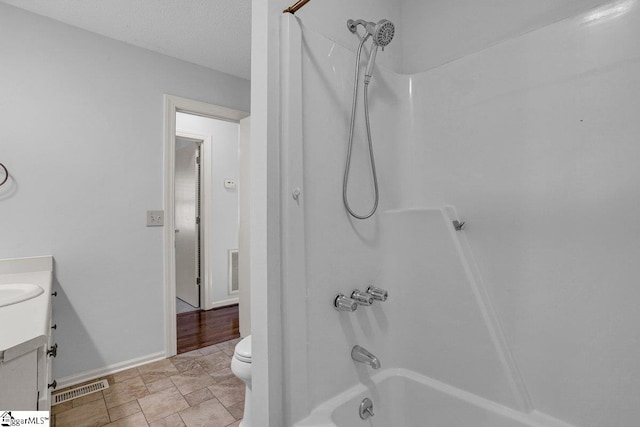 full bathroom with vanity, toilet, a textured ceiling, and shower / bathing tub combination