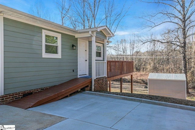 view of exterior entry with a patio area and a wooden deck