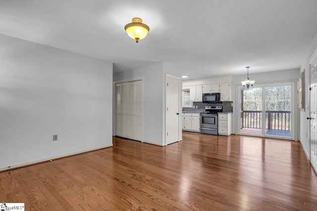 unfurnished living room featuring hardwood / wood-style floors and a chandelier