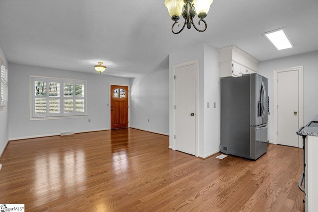 kitchen featuring stainless steel refrigerator with ice dispenser, white cabinets, and light wood-type flooring