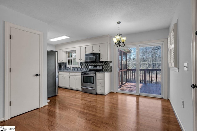 kitchen featuring a notable chandelier, decorative backsplash, white cabinets, pendant lighting, and stainless steel appliances