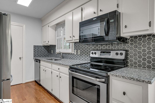 kitchen featuring light stone countertops, white cabinetry, sink, light hardwood / wood-style flooring, and stainless steel appliances