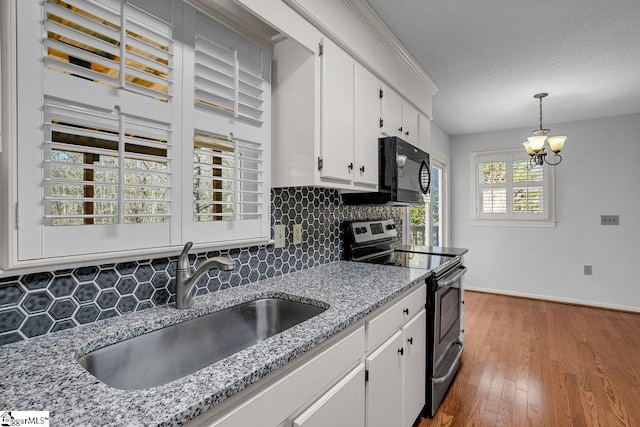 kitchen with hanging light fixtures, sink, backsplash, white cabinets, and stainless steel electric range