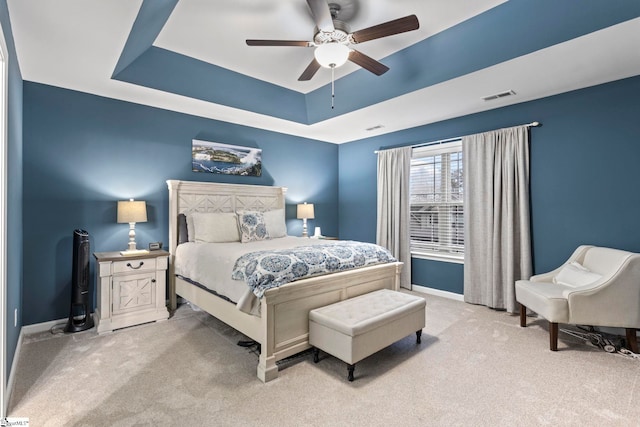 bedroom with ceiling fan, a raised ceiling, and light carpet