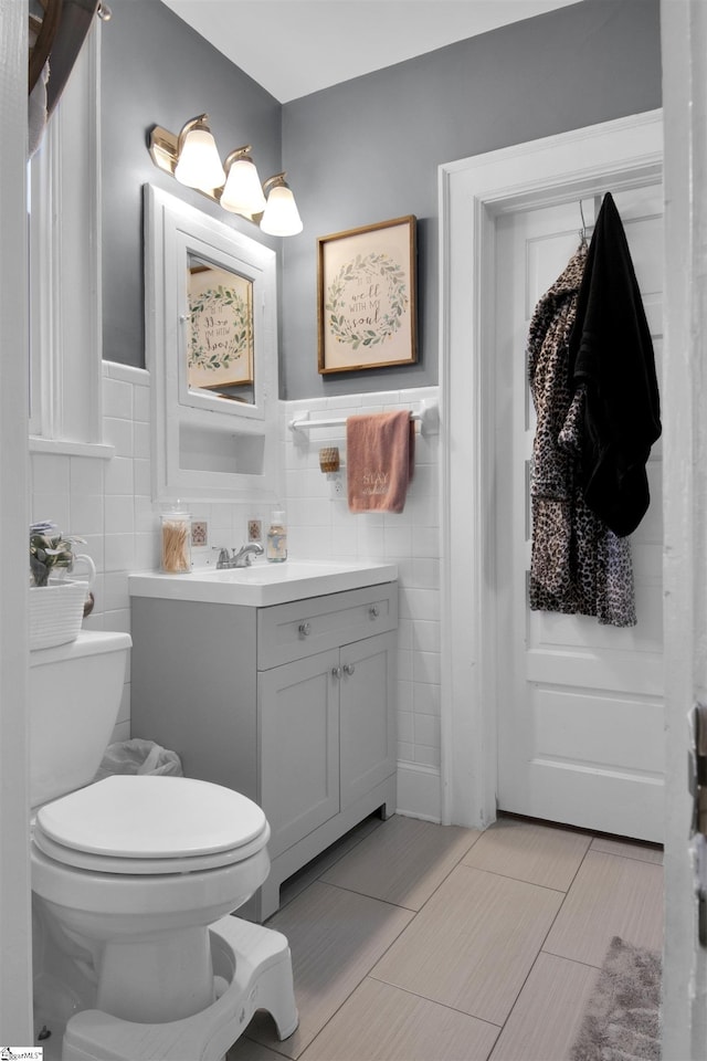 bathroom with tile patterned floors, tile walls, toilet, and vanity