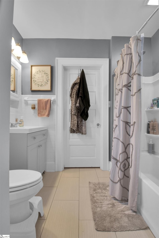 full bathroom with toilet, shower / tub combo, tile walls, tile patterned floors, and vanity