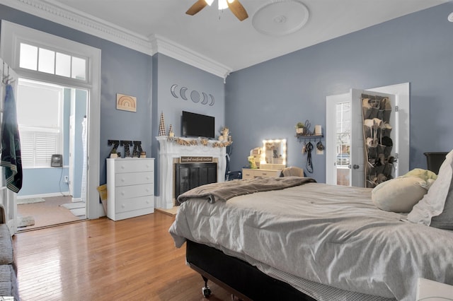 bedroom with ceiling fan, connected bathroom, crown molding, and hardwood / wood-style floors