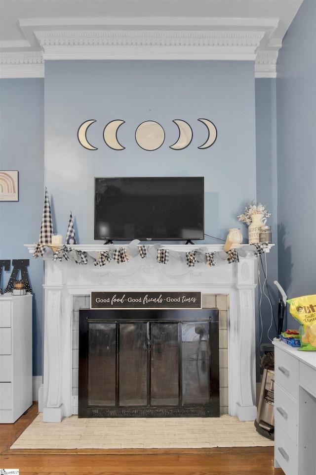 room details with wood-type flooring, a tile fireplace, and ornamental molding