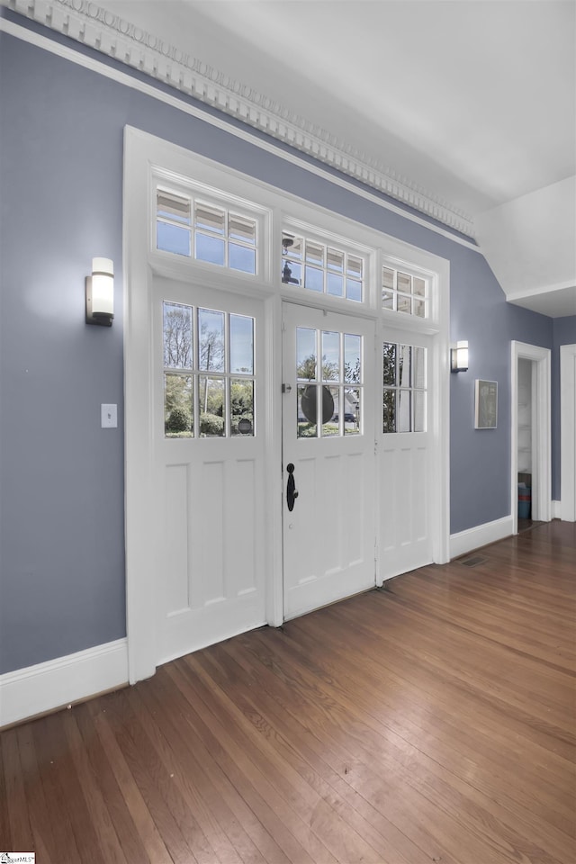 entrance foyer featuring wood-type flooring, crown molding, and lofted ceiling