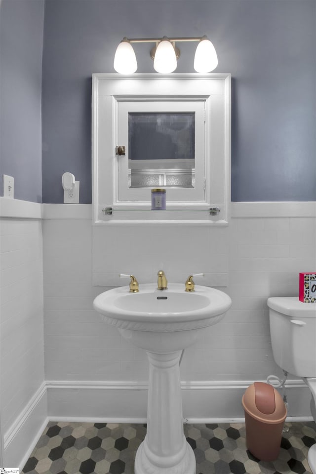 bathroom featuring tile walls and toilet