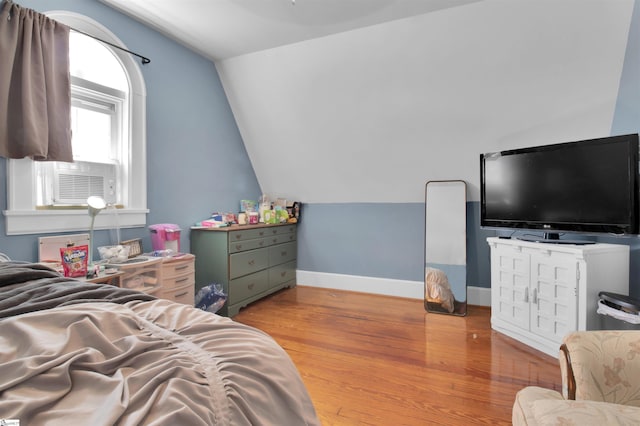 bedroom with light wood-type flooring, vaulted ceiling, and cooling unit