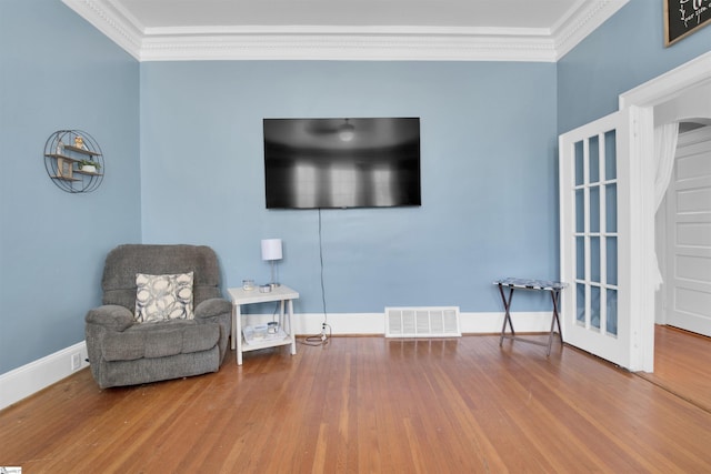 sitting room with ornamental molding and wood-type flooring