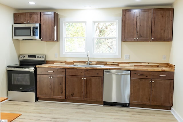 kitchen featuring sink, wooden counters, light hardwood / wood-style floors, and stainless steel appliances