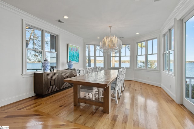 sunroom featuring a chandelier, a water view, and a wealth of natural light