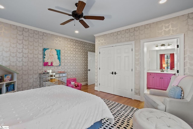 bedroom with ensuite bathroom, ceiling fan, light wood-type flooring, ornamental molding, and a closet