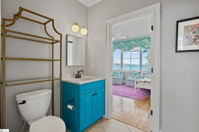 bathroom with tile patterned floors, vanity, toilet, a water view, and crown molding