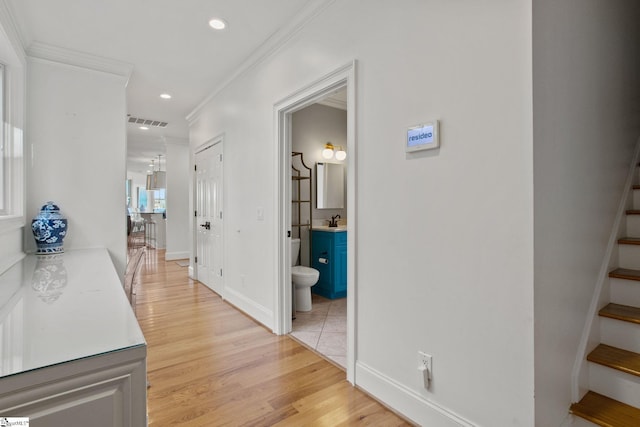 hallway featuring sink, light hardwood / wood-style floors, and ornamental molding