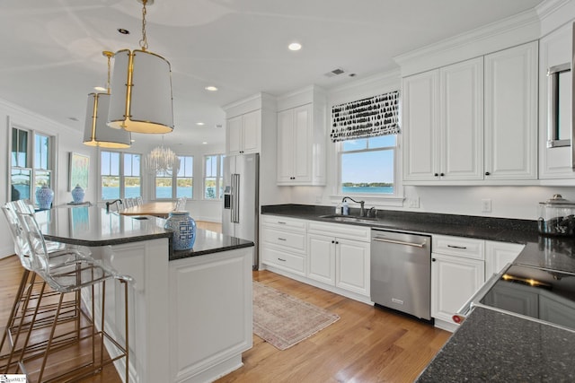 kitchen with sink, white cabinets, a water view, and stainless steel appliances