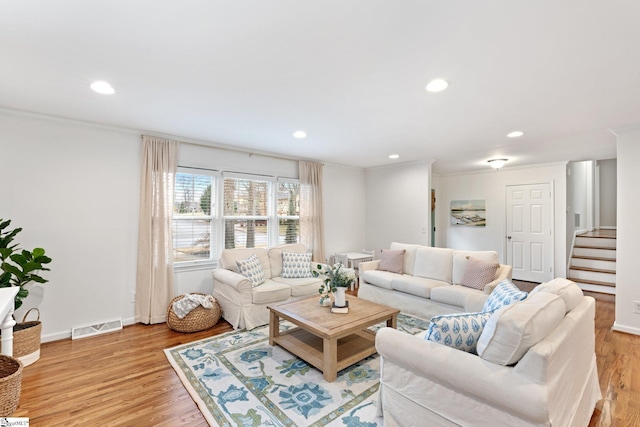 living room with ornamental molding and light hardwood / wood-style flooring