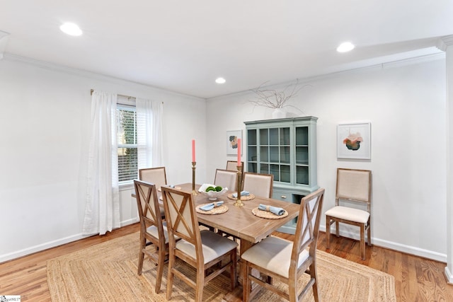 dining space featuring light wood-type flooring and ornamental molding